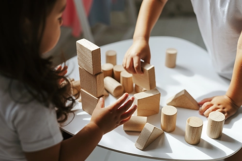 Children building with wooden blocks on a classroom table