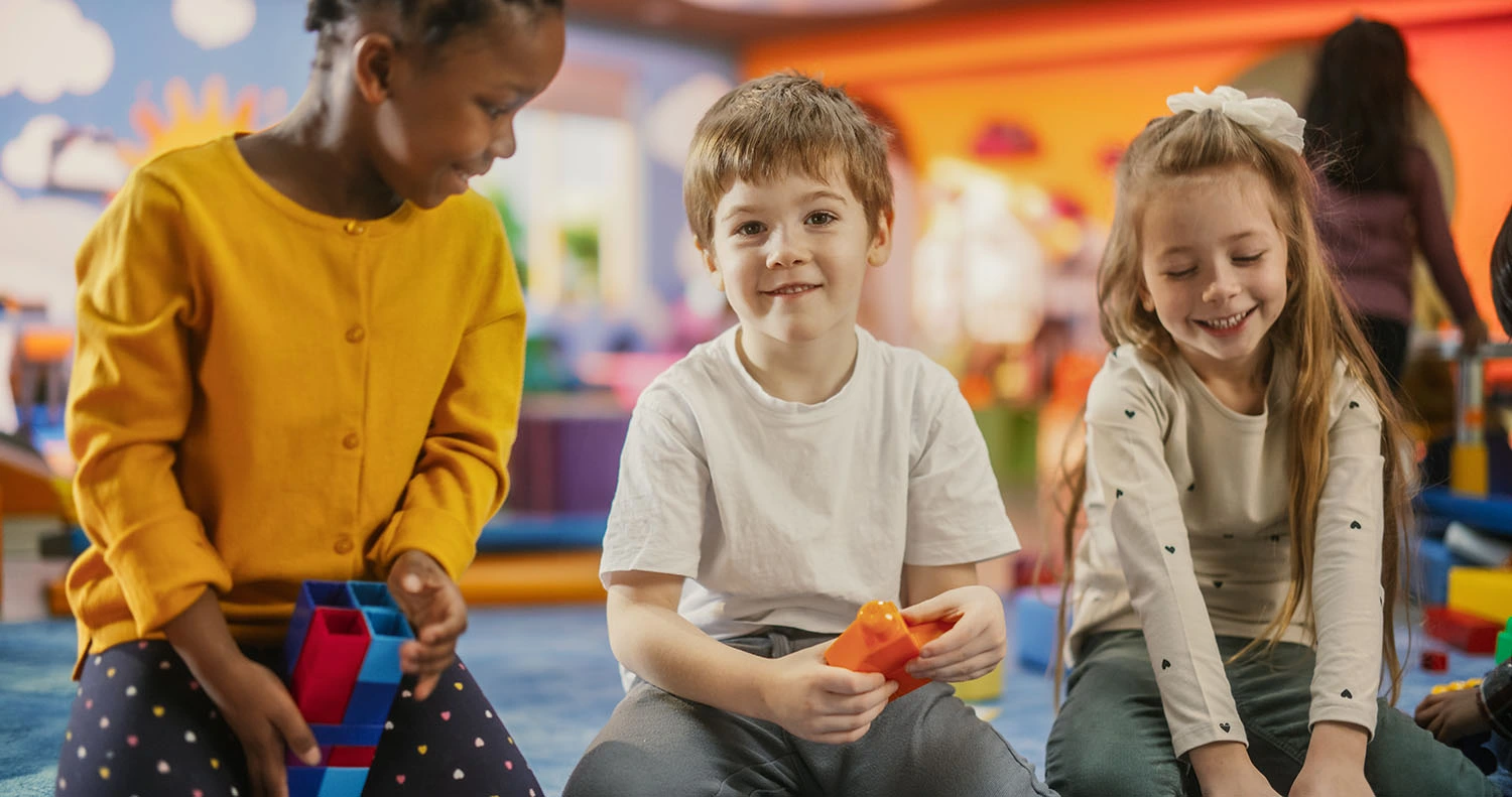 Three children playing together in a colourful classroom